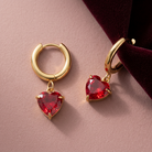 Julia Ruby Earrings Gold med röda hjärtan mot dämpat rosa och vinrött
