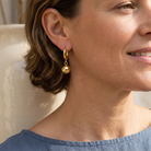 Linnéa Earrings Gold i närbild på modell med kort vågigt hår