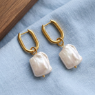 Elise Earrings Gold på ljusblå bomull med varm trädetalj