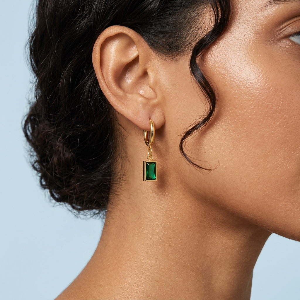 Aira Bottle Green Earrings Gold i närbild på örat mot blå bakgrund